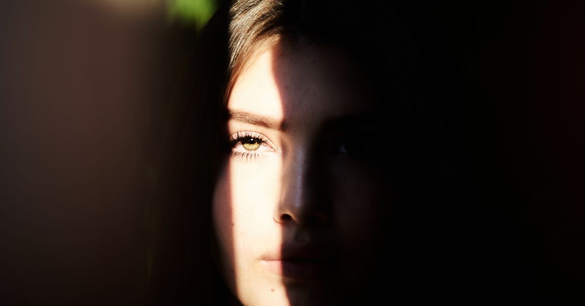 Rostro humano iluminado por luz lateral frente a una cámara en un entorno oscuro